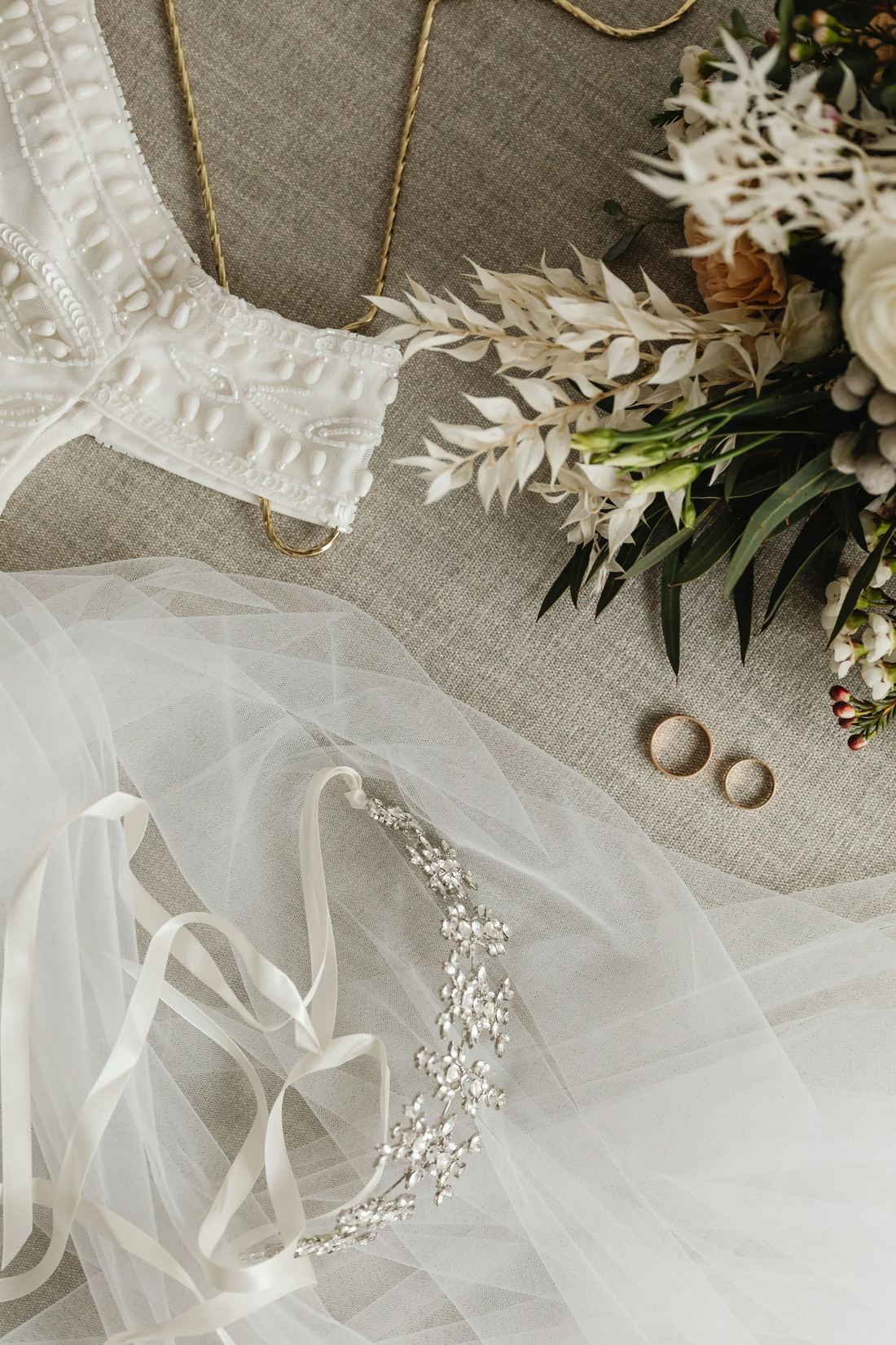 Bridal veil, hairpiece, and two gold bands laid on linen.