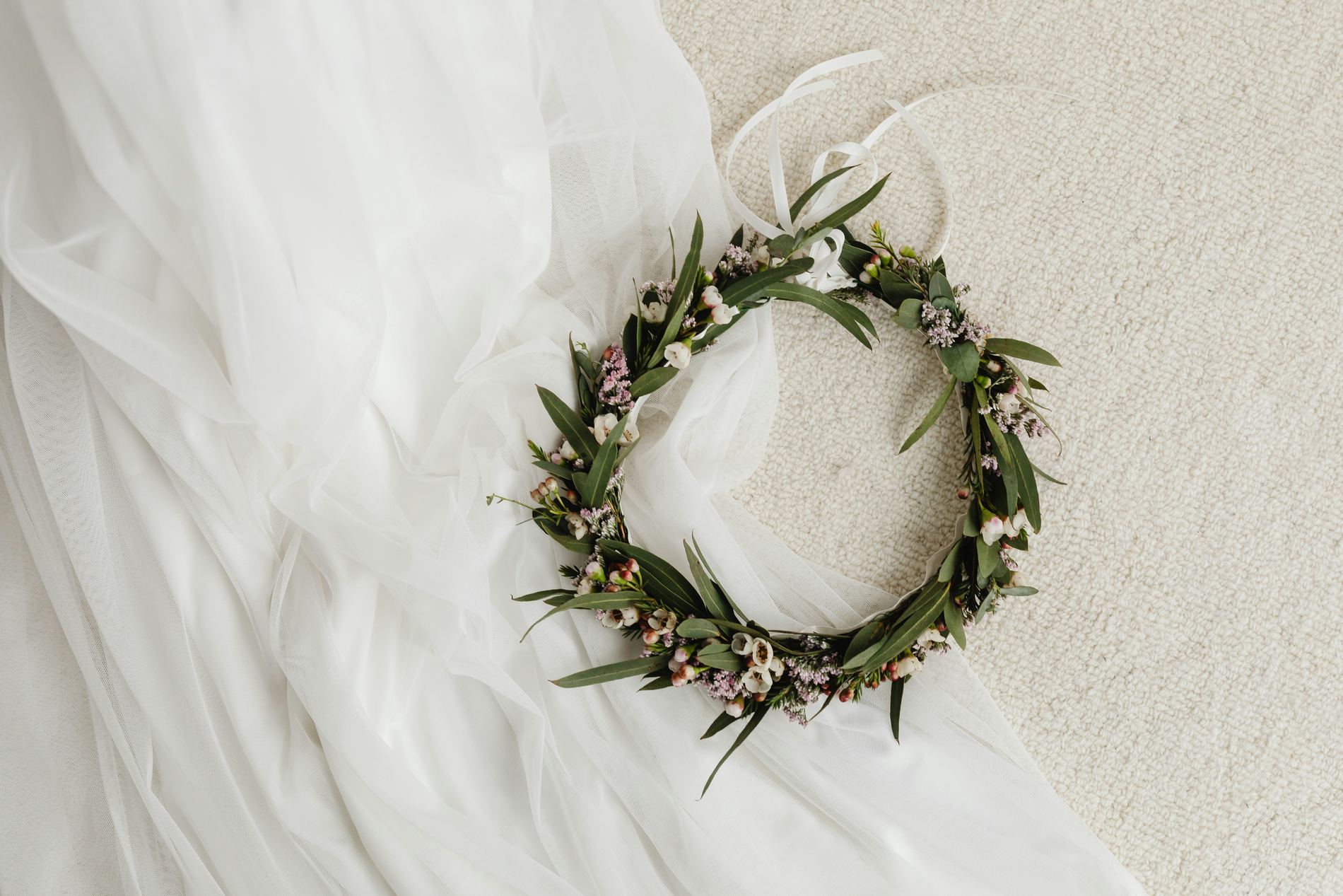 A eucalyptus and wax-flower crown resting on a bride's tulle veil.